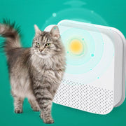 Gray long-haired cat next to a white automatic cat litter box deodorizer and air purifier device